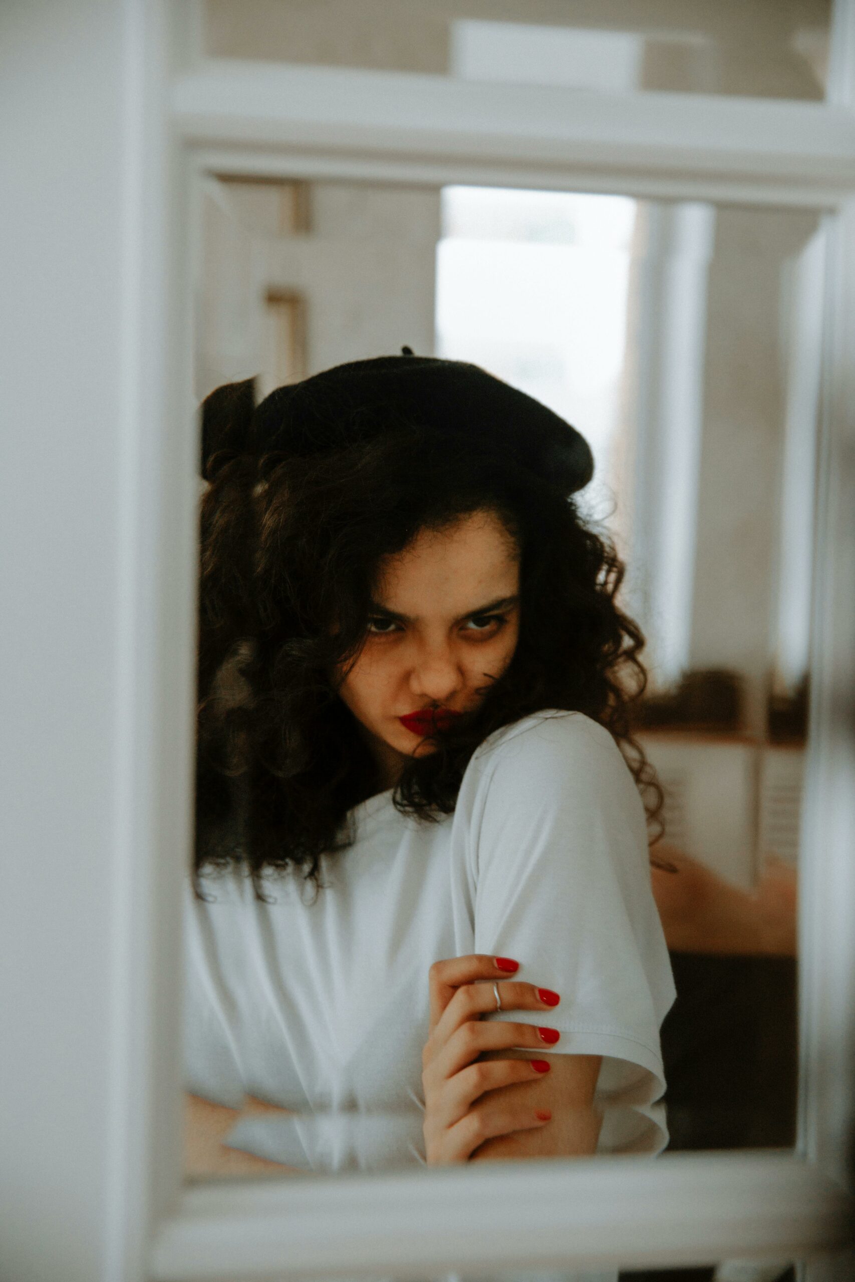 Reflective portrait of a woman with curly hair and intense expression indoors.