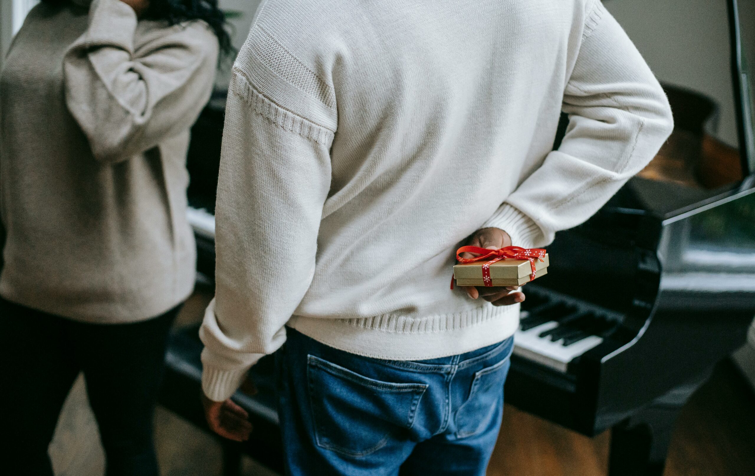 An intimate moment of gift-giving during the holiday season by the piano.