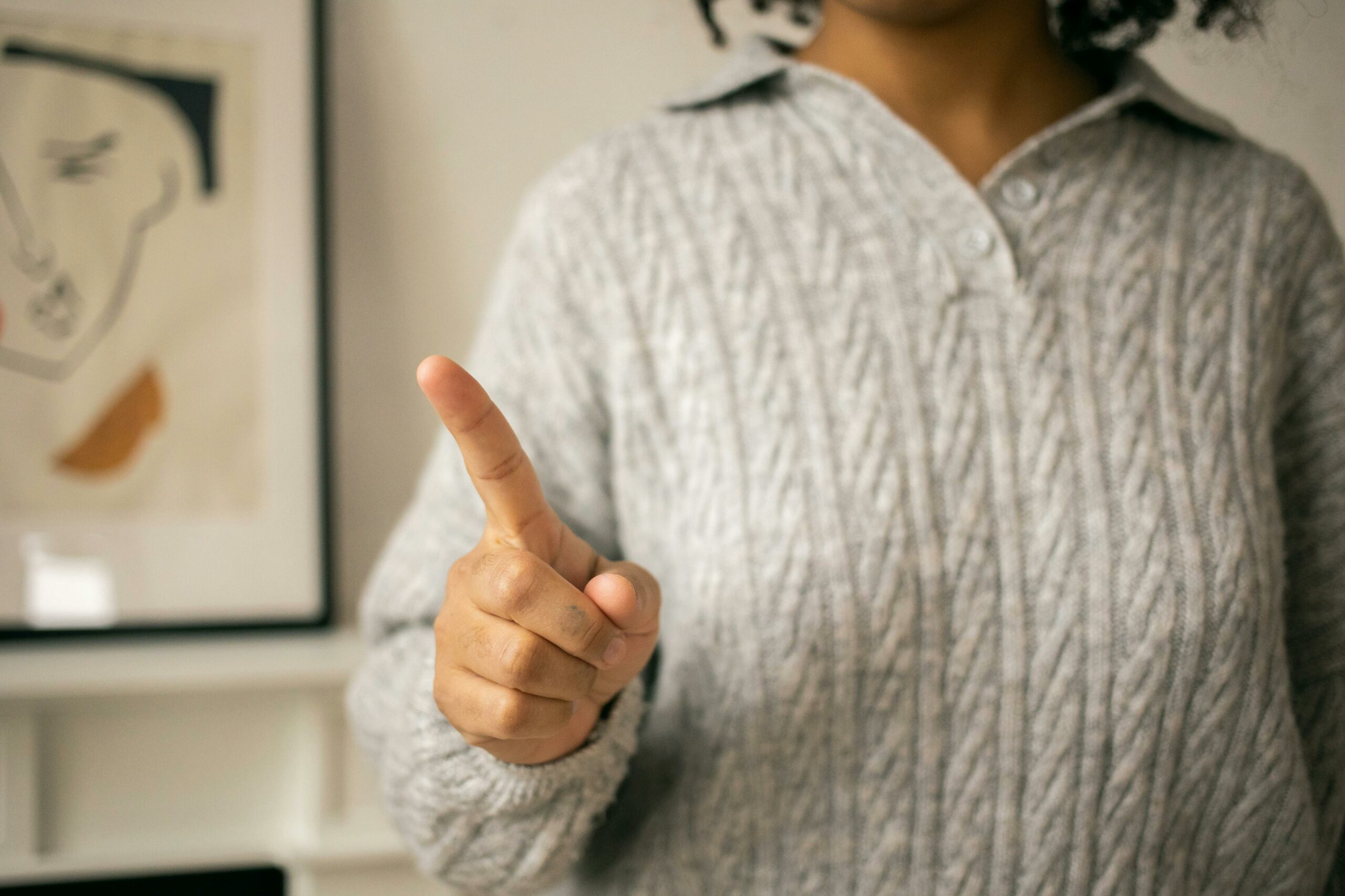 A close-up of a woman in a sweater gesturing 'no' indoors, capturing emotion.