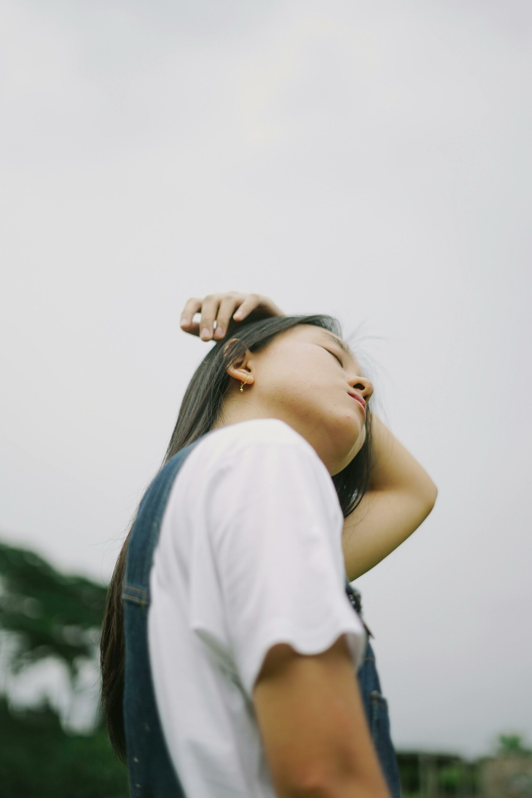 Young woman in peaceful outdoor setting with eyes closed, conveying calm and tranquility.